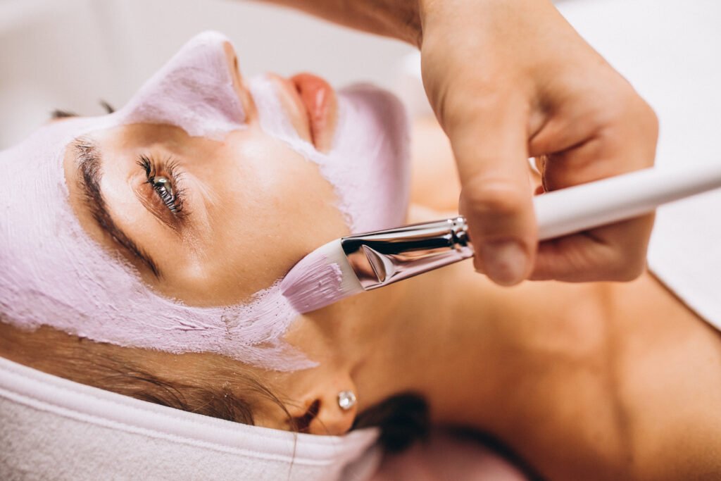cosmetologist applying mask on a face of client in a beauty salon
